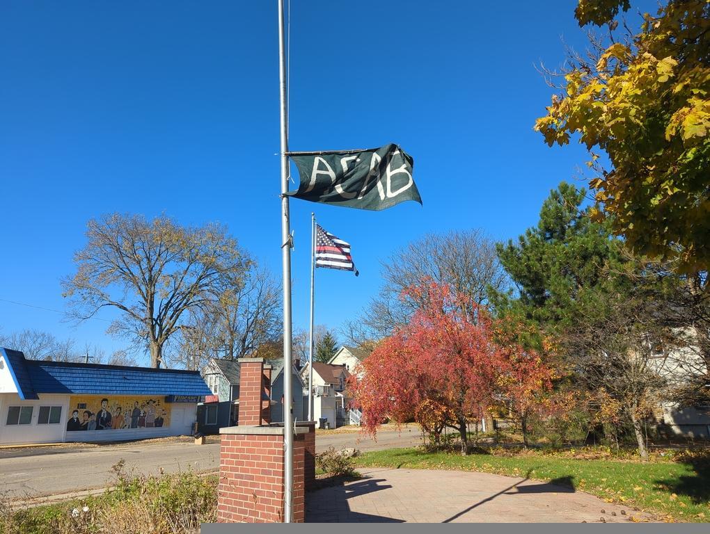 A black flag on a police monument flagpole which reads "ACAB"