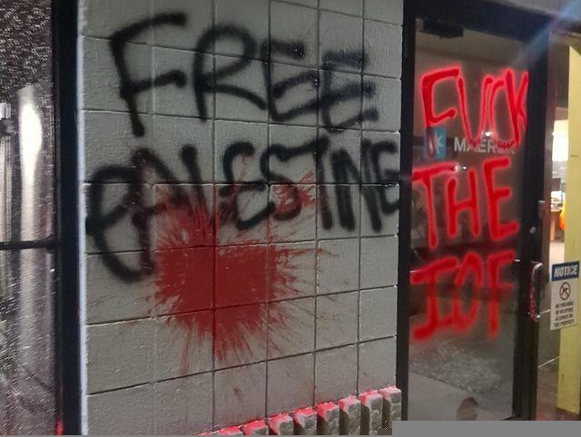 "FREE PALESTINE" and "FUCK THE IOF" are written on the exterior wall and door of a MAERSK office, with a large red paint splatter on the wall.
