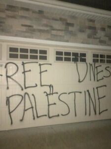 A garage door is spray-painted with "Free Palestine" and "Divest"